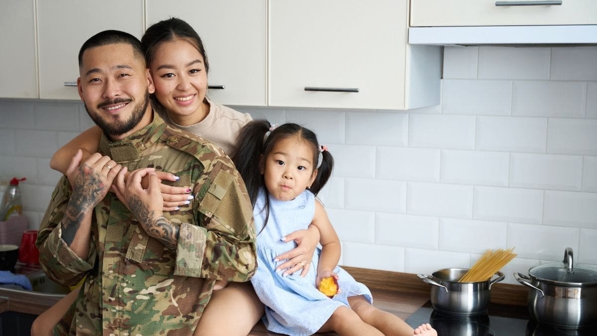 A father in military fatigues with his wife and daughter in their kitchen
